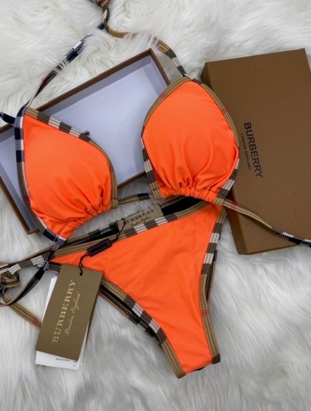 Orange bikini set with Burberry branding on a white fur background